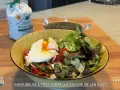 Une assiette colorée de salade de lentilles garnie d'un œuf poché, de légumes frais et de tomates. Un sac de lentilles vertes est visible en arrière-plan.