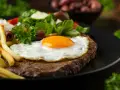 Un plat de steak a cheval savoureux avec un œuf au plat, des frites dorées, du riz blanc et une salade fraîche.