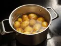Pommes de terre entières dans une casserole d'eau bouillante, prêtes pour le temps de cuisson à l'eau.