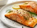 Deux pavés de saumon parfaitement cuits au four, assaisonnés de poivre et d'aneth, accompagnés de rondelles de citron. Le temps de cuisson saumon four idéal pour un plat savoureux.
