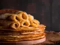 Pile de crêpes dorées, certaines roulées, prêtes à être dégustées. Une astuce pour garder les crêpes au chaud : les empiler ainsi !