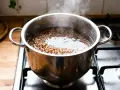 Une casserole de sarrasin bout sur la cuisinière, montrant comment cuire le sarrasin pour un repas sain.