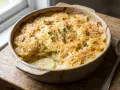 Un gratin de pommes de terre crémeux et doré, garni de thym frais, prêt à être dégusté.