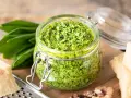 Pesto d'ail des ours dans un bocal, avec des feuilles fraîches, du parmesan et des noix. Une recette maison facile à réaliser.