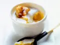 Délicieux dessert lait de coco crémeux avec des morceaux de fruits caramélisés. Une cuillère en est prête à être dégustée.