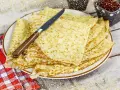 Pile de crêpes bretonnes dorées sur une assiette, prêtes à être dégustées. Un couteau est posé dessus.