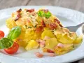 Un délicieux gratin de pommes de terre et lardons, doré au four, servi avec des tomates cerises et du basilic. Un plat réconfortant et savoureux.