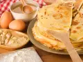 Pile de crêpes dorées, ingrédients pour leur origine : œufs, amandes, farine, miel. Un délice sucré.