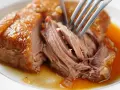 Une rouelle de porc au four, tendre et juteuse, est effilochée à la fourchette dans son jus doré.