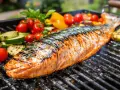 Un poisson entier, grillé à la perfection, avec des légumes colorés autour. Un délice de poisson au barbecue.