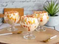 Trois coupes de crème anglaise avec une île flottante meringuée, nappées de caramel et d'amandes effilées.