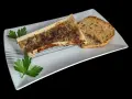 Un os à moelle rôti, assaisonné et garni de persil, servi avec des toasts grillés sur une assiette blanche.