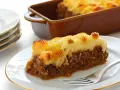 Une part de hachis parmentier, prêt pour la cuisson chaleur tournante, sur une assiette blanche.