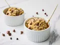 Deux ramequins blancs remplis de pâte à cookie aux pépites de chocolat, prêts à être dégustés.