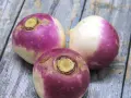 Trois navets violets et blancs sur une table en bois. Parfait pour une recette navet réconfortante.