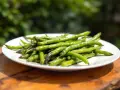 Une assiette de haricots verts grillés, une portion parfaite par personne pour un repas sain et savoureux en extérieur.