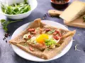 Une galette de sarrasin garnie d'un œuf au plat, de lardons et de champignons. Un délice pour un petit-déjeuner ou un brunch.