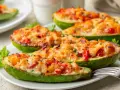 Courgettes farcies appétissantes, garnies de fromage fondant et de légumes colorés, prêtes à être dégustées.