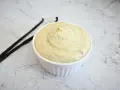 Un bol de ganache chocolat blanc onctueuse, parsemée de points de vanille, avec deux gousses de vanille à côté.