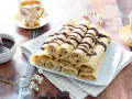 Crêpes roulées, nappées de chocolat, accompagnées d'une tasse de thé. Une recette crêpe raffinée pour un goûter gourmand.