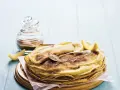Pile de crêpes au lait entier, saupoudrées de sucre et de cannelle, garnies de quartiers de citron. Un délice simple et gourmand.
