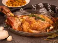 Une succulente épaule d'agneau rôtie à la perfection, garnie de romarin frais, prête à être dégustée.