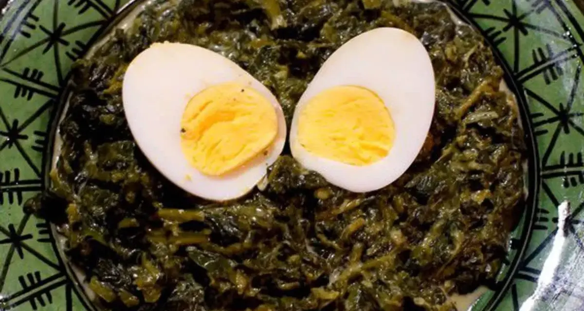 Un plat d'épinards à la crème, parsemé de deux moitiés d'œufs durs, sur une assiette verte décorée.