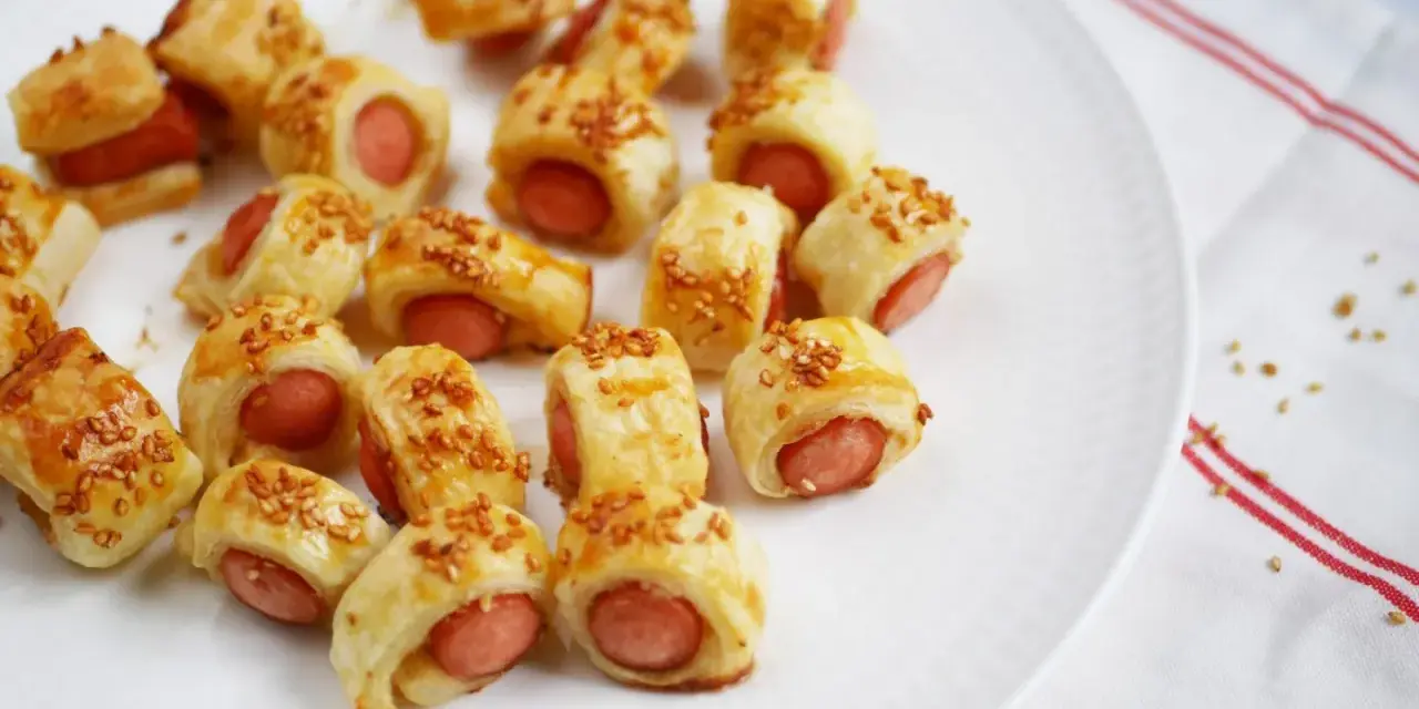 Une assiette de feuilleté saucisse dorés, parsemés de graines de sésame. Parfait pour un apéritif gourmand.