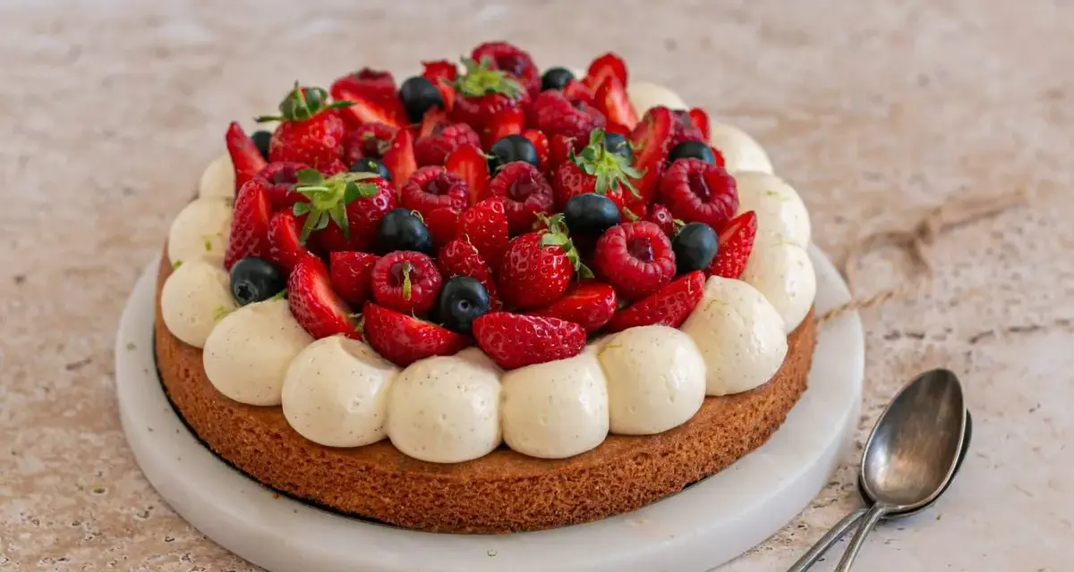 Un délicieux gâteau aux fraises, garni de framboises, myrtilles et crème vanillée. Parfait pour une occasion spéciale.