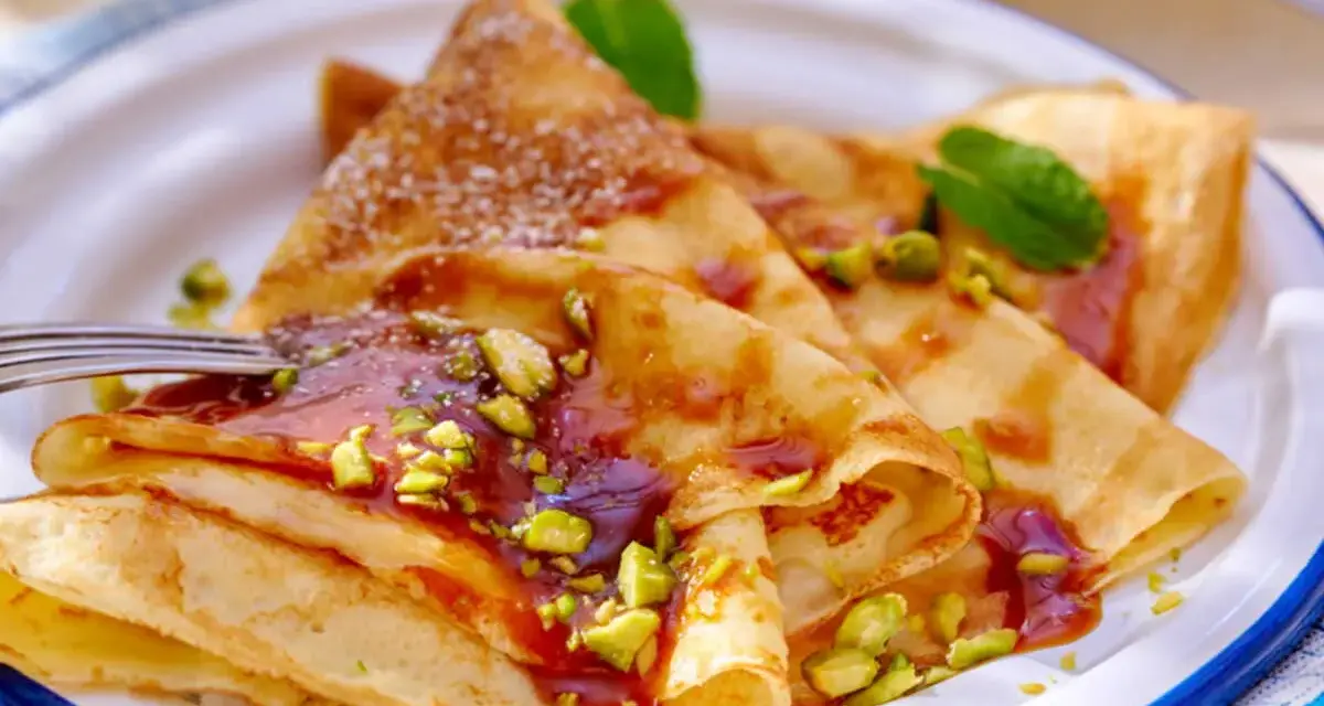 Délicieuses crêpes salées au beurre, garnies de pistaches concassées et d'un coulis rouge. Une touche de menthe apporte de la fraîcheur.