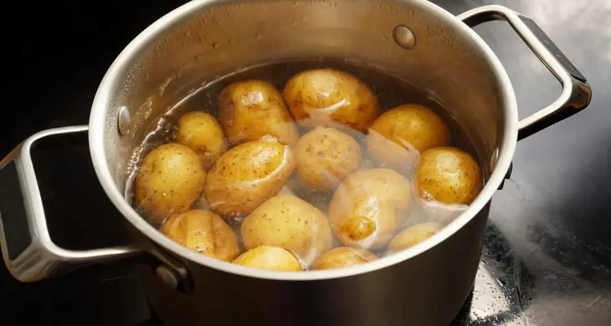 Pommes de terre entières dans une casserole d'eau bouillante, prêtes pour le temps de cuisson à l'eau.