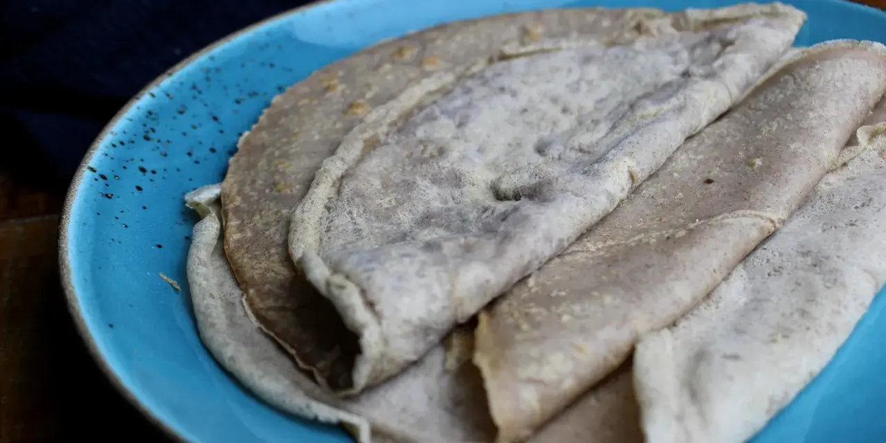 Galettes de sarrasin, naturellement sans gluten, sur une assiette bleue. La farine de blé noir donne cette texture rustique.