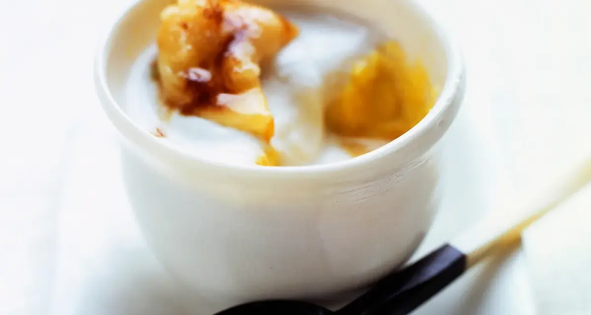 Délicieux dessert lait de coco crémeux avec des morceaux de fruits caramélisés. Une cuillère en est prête à être dégustée.