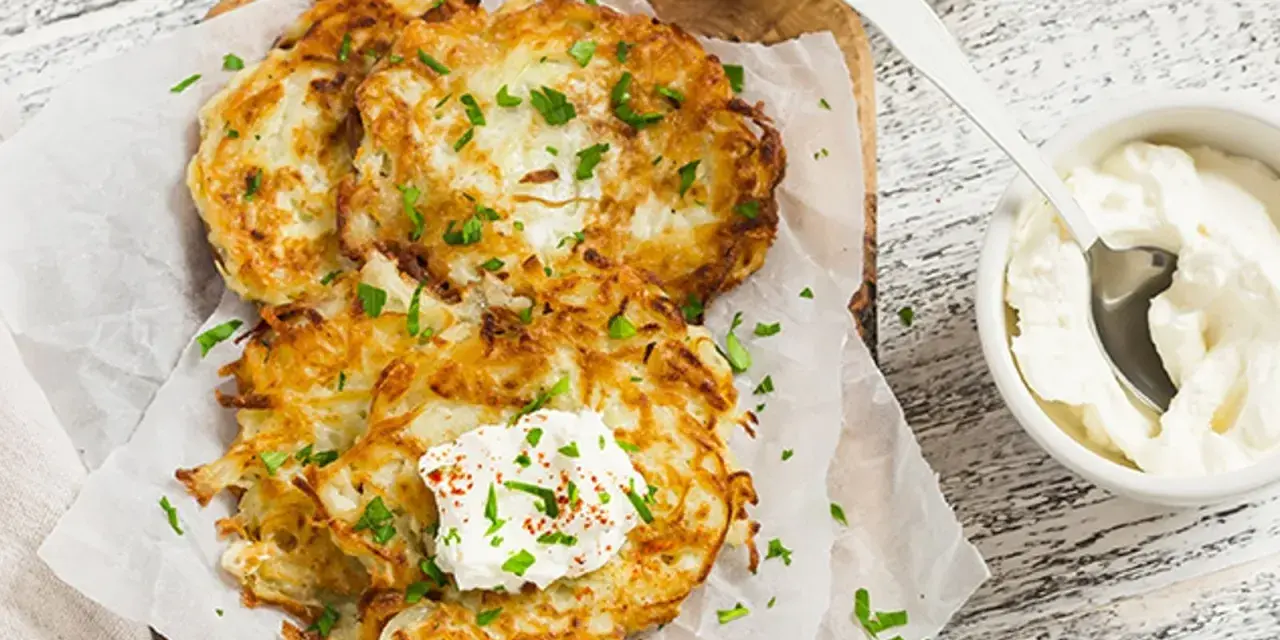Délicieux rapé de pomme de terre doré, garni de crème fraîche et de persil, prêt à être dégusté avec une touche de paprika.