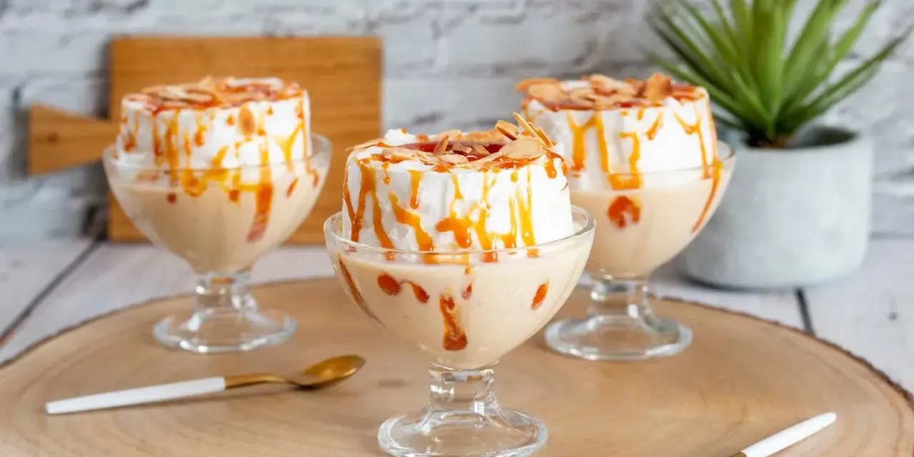Trois coupes de crème anglaise avec une île flottante meringuée, nappées de caramel et d'amandes effilées.
