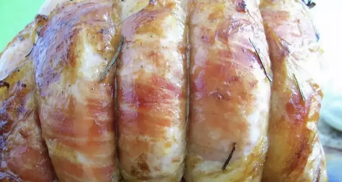 Un délicieux roti de veau, enveloppé de lard et parsemé de romarin, prêt à être dégusté.