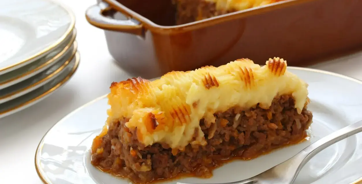 Une part de hachis parmentier, prêt pour la cuisson chaleur tournante, sur une assiette blanche.