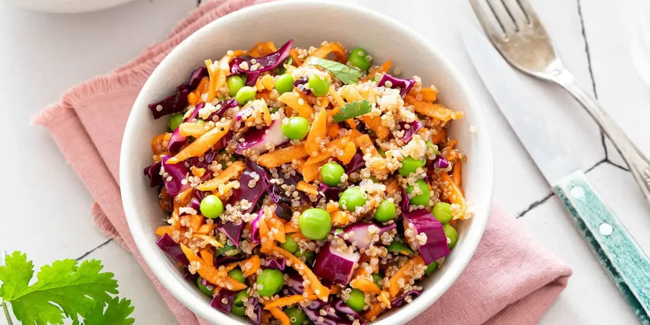 Salade quinoa colorée avec carottes râpées, chou rouge, petits pois et edamame. Un plat sain et savoureux.