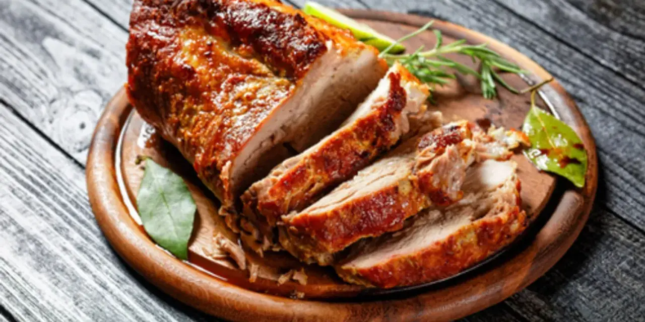 Un rôti de porc au four, coupé en tranches, sur une planche en bois. Le temps cuisson rôti de porc au four moelleux est parfait pour ce plat savoureux.
