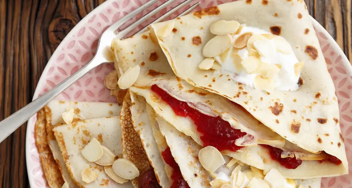 Crêpes fines garnies de confiture et de crème, parsemées d'amandes effilées. Une délicieuse recette crêpe sans beurre pour un goûter léger.