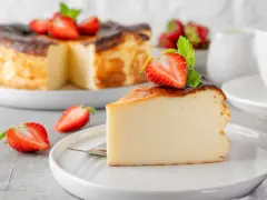 Tranche de gâteau au fromage brûlé, garnie de fraises et de menthe. Un dessert facile qui impressionne, parfait pour toute occasion.