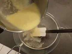 Verser la crème anglaise à travers une passoire fine pour obtenir une texture lisse.