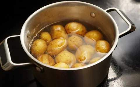Pommes de terre entières dans une casserole d'eau bouillante, prêtes pour le temps de cuisson à l'eau.