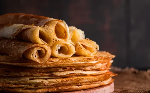 Pile de crêpes dorées, certaines roulées, prêtes à être dégustées. Une astuce pour garder les crêpes au chaud : les empiler ainsi !