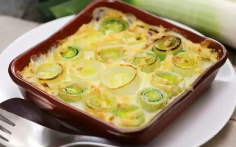 Un délicieux gratin de poireaux crémeux, prêt à être dégusté. Les poireaux coupés en rondelles sont nappés d'une sauce onctueuse et gratinés à la perfection.