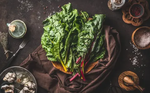 Blettes fraîches, ail, herbes et épices pour une délicieuse recette blette. Huile d'olive et sel complètent les ingrédients.