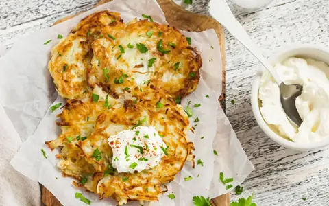 Délicieux rapé de pomme de terre doré, garni de crème fraîche et de persil, prêt à être dégusté avec une touche de paprika.