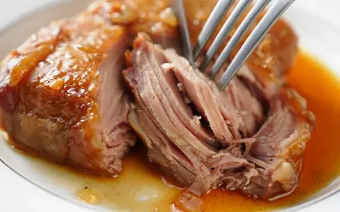 Une rouelle de porc au four, tendre et juteuse, est effilochée à la fourchette dans son jus doré.