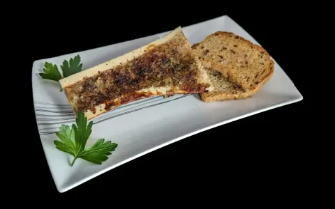 Un os à moelle rôti, assaisonné et garni de persil, servi avec des toasts grillés sur une assiette blanche.