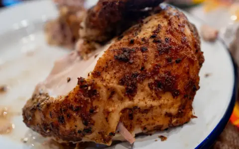 Un morceau de poulet braisé, doré et savoureux, est servi sur une assiette blanche.